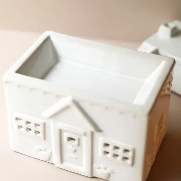 White ceramic house-shaped wax-melt burner on a beige background