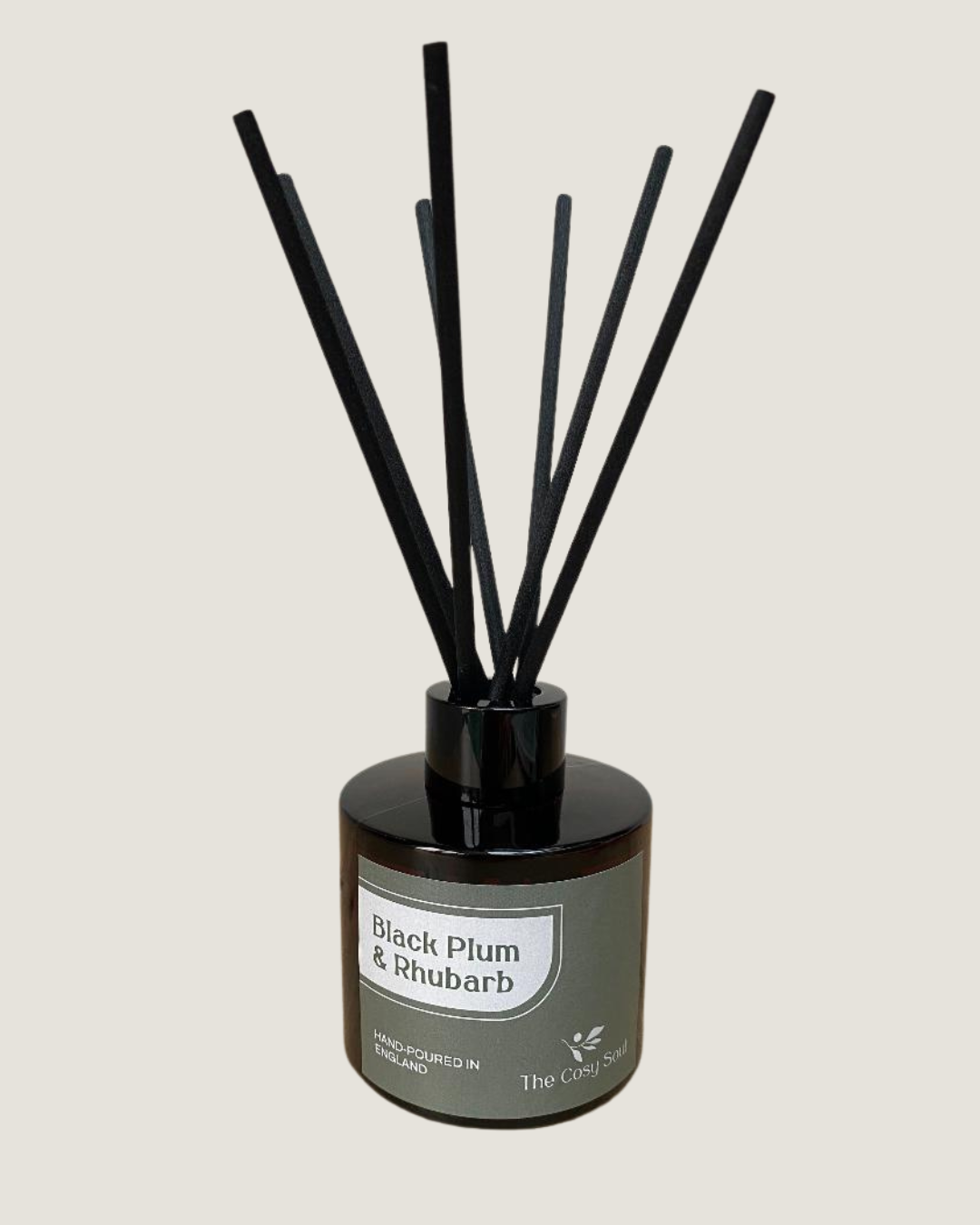 The Cosy Soul Reed diffuser with black reeds and a brown bottle labelled 'Black Plum & Rhubarb' on a light grey background