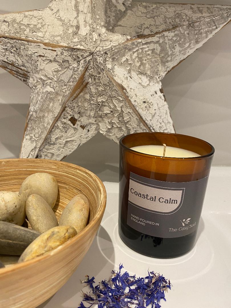 The Cosy Soul Candle fragranced 'Coastal Calm' next to coastal themed ornaments.