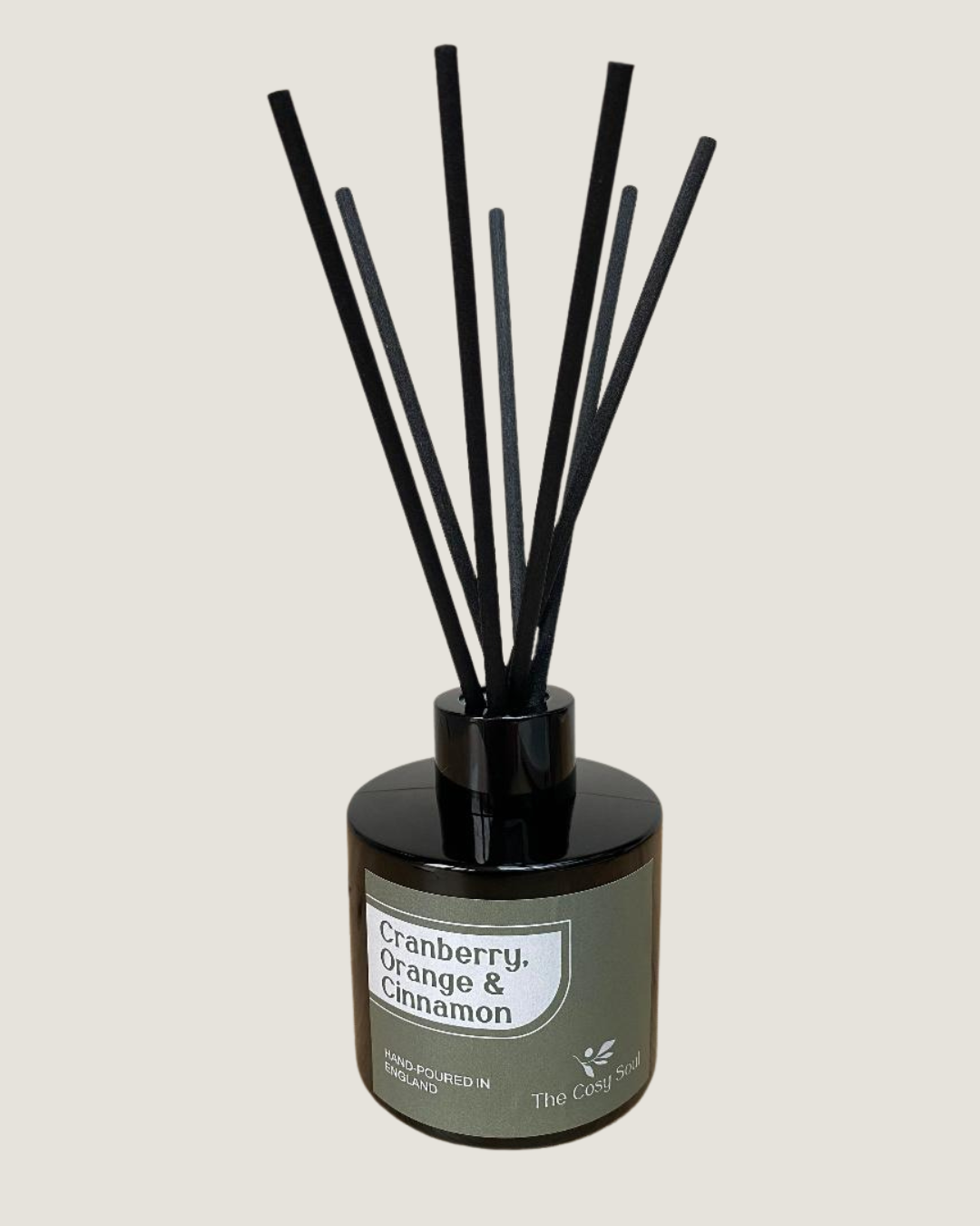Reed diffuser with black reeds and brown bottle labelled 'Cranberry Orange & Cinnamon' on a light grey background