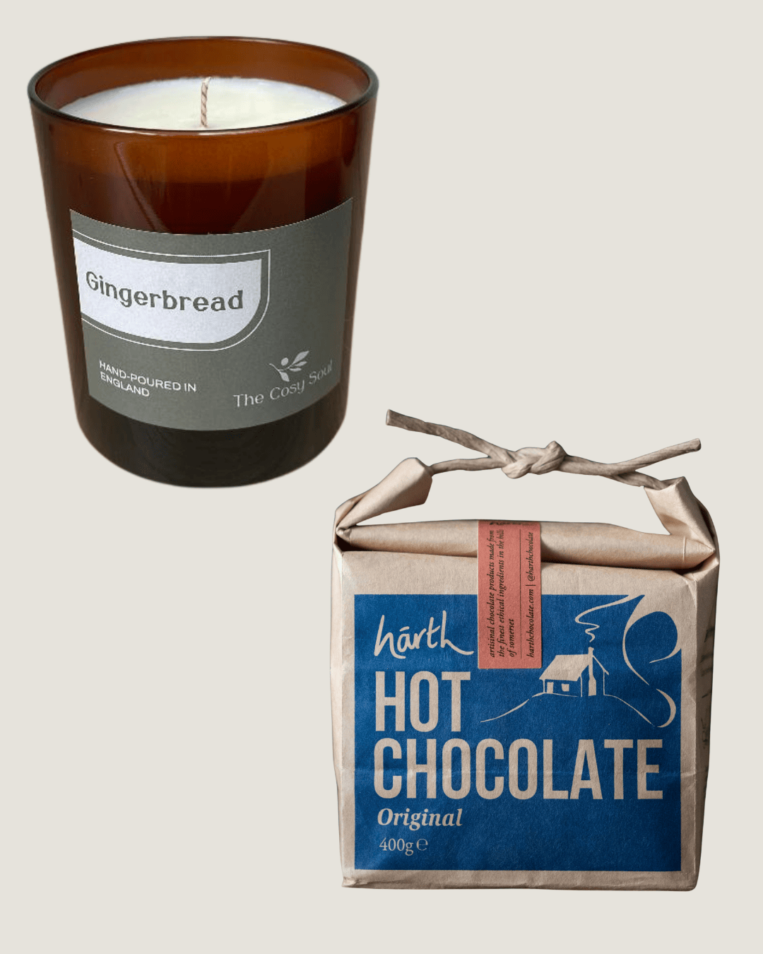 The Cosy Soul Gingerbread candle in a brown glass container next to a box of hot chocolate on a light grey background