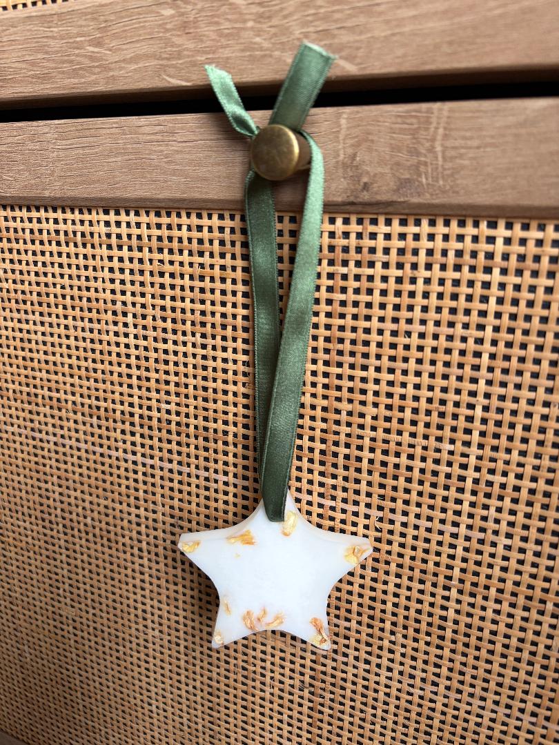 Star-shaped wax melt hanging with a green ribbon on a textured surface