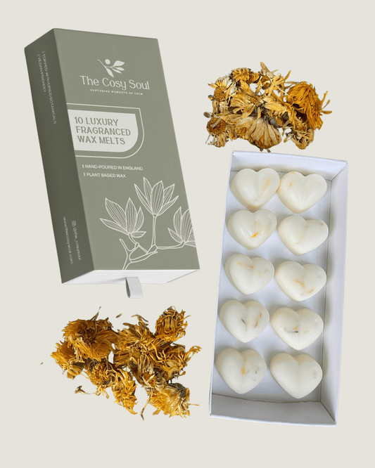 Box of heart-shaped honey and tobacco wax melts with 'The Cosy Soul' packaging and marigolds on a light background