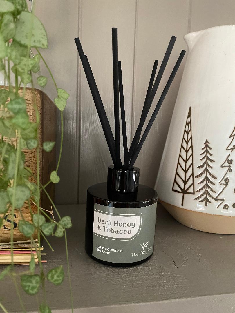 The Cosy Soul Diffuser bottle labelled 'Dark Honey & Tobacco' with black reeds on a shelf