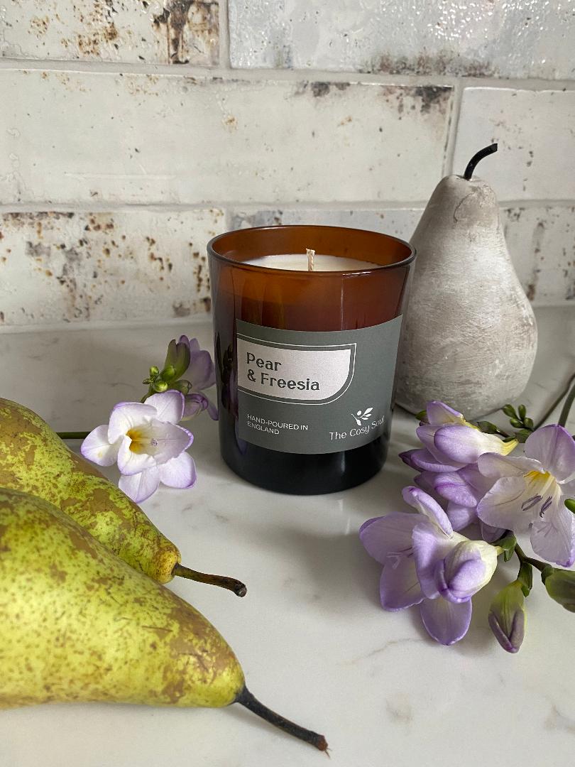 Pear & Freesia candle from The Cosy Soul with pears and flowers on a marble surface.