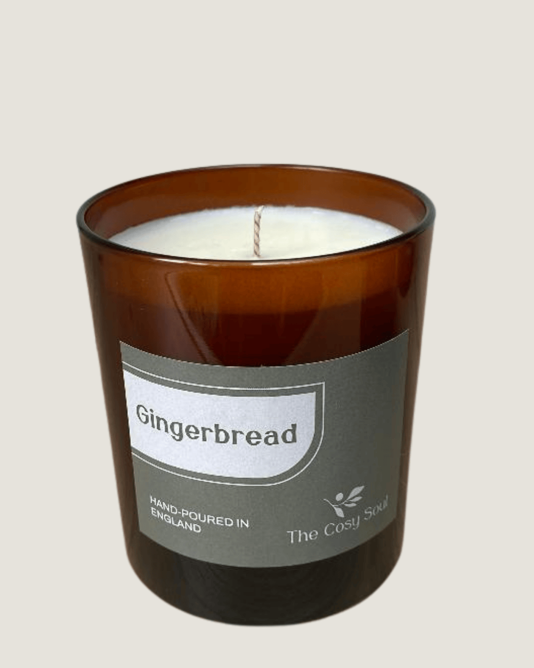 The Cosy Soul Gingerbread candle in a brown glass jar with a label on a beige background