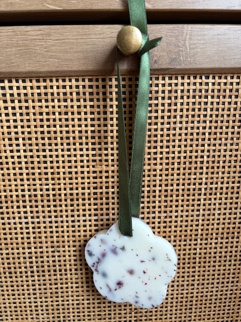 Hanging wax melt flower with a green ribbon on a textured surface