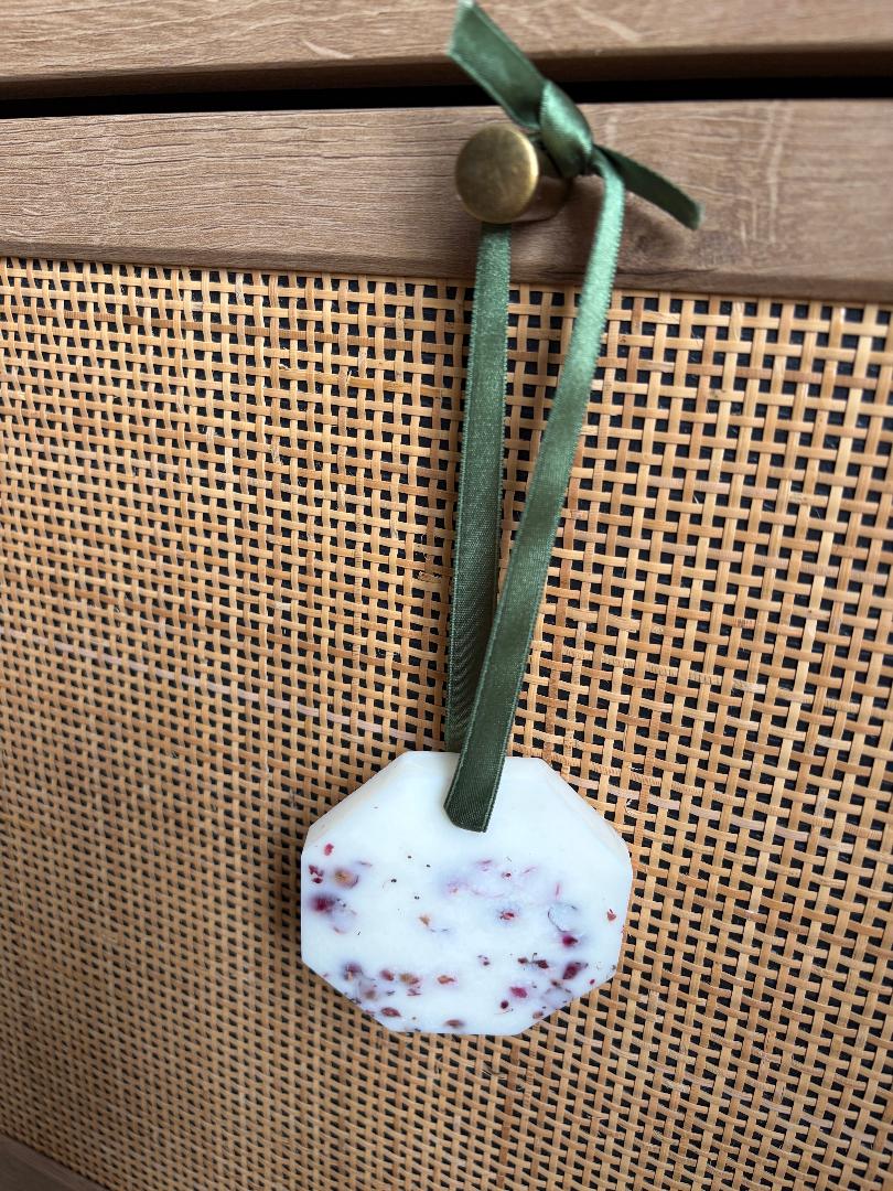 Hanging wax melt hexagon on a green ribbon with a wooden background