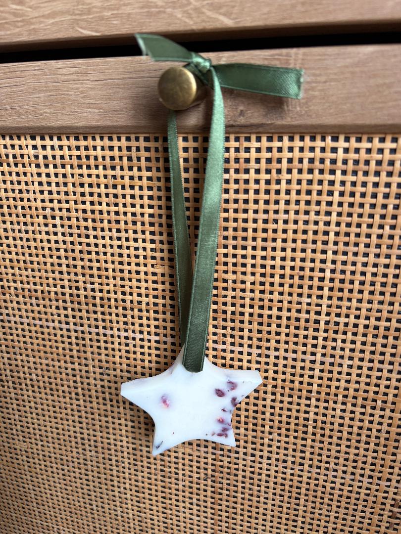 Wax Melt Hanging star tied on green ribbon with a wooden background