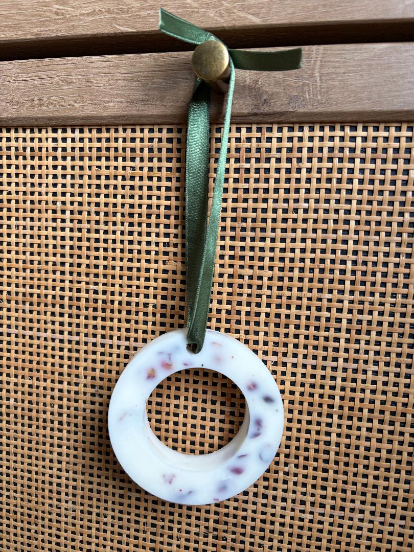 Hanging wax melt wreath with a green ribbon on a wooden background