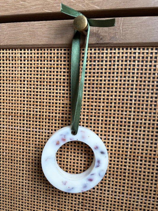 Hanging wax melt wreath with a green ribbon on a wooden background
